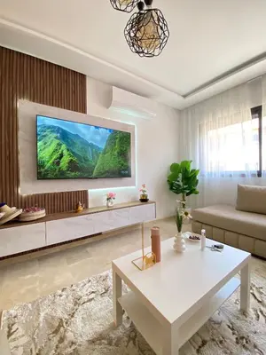 a living room with a couch and a tv on a wall at Refined stay with 4 pools in Marrakech in Marrakech