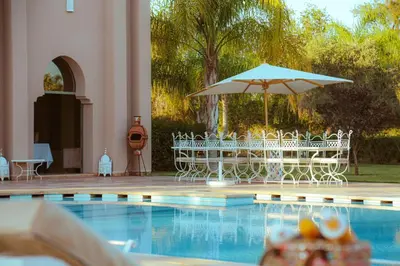a table and chairs with an umbrella next to a pool at Palais Soufi 8 chambres in Marrakech