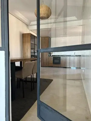 a dining room with a table and a glass door at Residence La Perle de Atlas Appartement in Marrakech