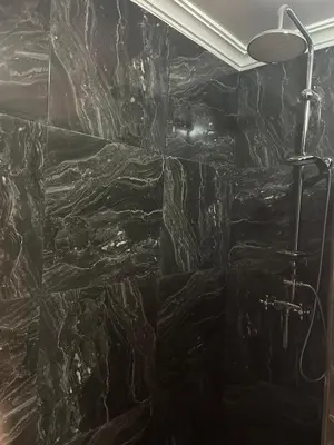 a bathroom with a black stone wall at Residence La Perle de Atlas Appartement in Marrakech