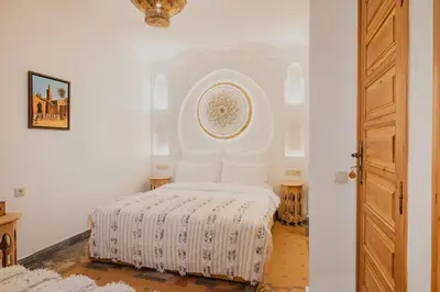 a white bedroom with a bed with white sheets at Riad Al Mechouar in Marrakech