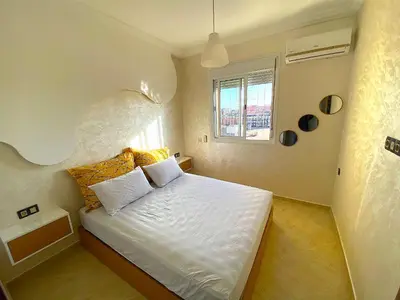 a bedroom with a white bed with a window at Appartement à Marrakech confortable et équipe in Marrakech