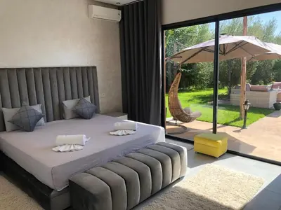 a bedroom with a bed and an umbrella and a patio at Villa privée in Taazout