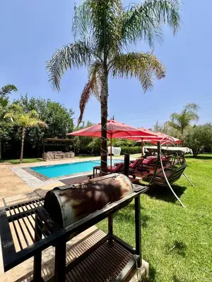 a pool with a picnic table and a palm tree at Villa privée in Taazout