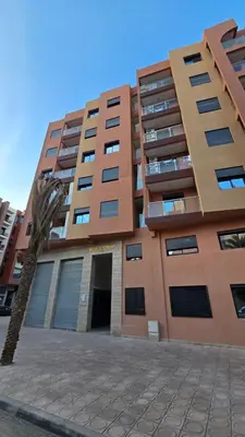 a tall building with a palm tree in front of it at Charming Marrakech Appartement in Marrakech