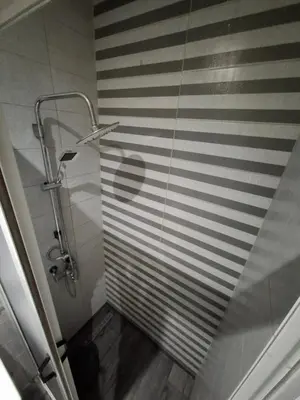 a bathroom with a shower and a striped wall at Modern Marrakech Apartment in Marrakech