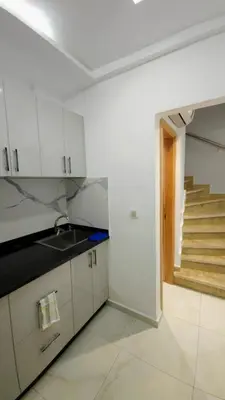 a kitchen with white cabinets and a sink and stairs at Charming Marrakech Duplex in Marrakech