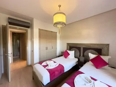 a bedroom with two beds and a chandelier at Marrakech Prestigia golf city in Marrakech