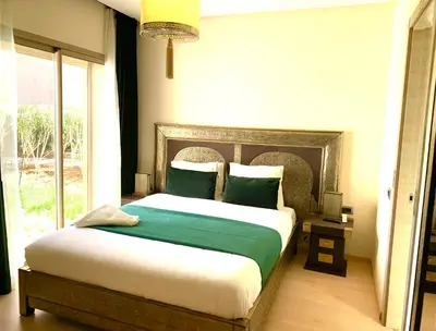 a bedroom with a large bed with green sheets and a window at Marrakech Prestigia golf city in Marrakech