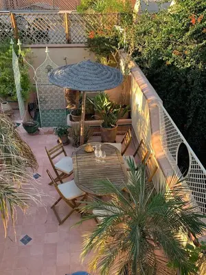 a patio with a table and a blue umbrella at RIAD VERT de Nina in Marrakech