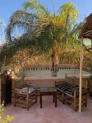 a patio with tables and chairs and palm trees at RIAD VERT de Nina in Marrakech