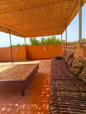 two beds under a straw roof on a patio at Domaine JJ in Marrakech