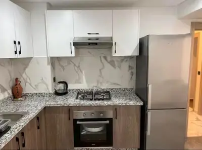 a kitchen with white cabinets and a stove and refrigerator at Résidence palmeraie gates Marrakech in Marrakech