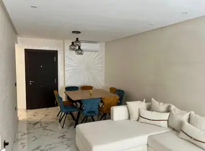 a living room with a white couch and a table at Résidence palmeraie gates Marrakech in Marrakech