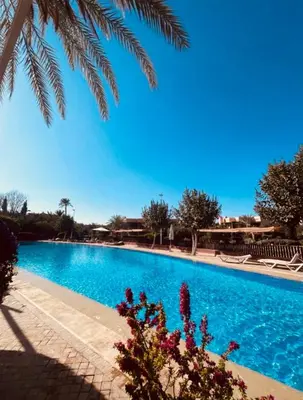 a swimming pool with a blue sky in the background at Palmeraie village , lieu exceptionnel avec jardin et piscine in Marrakech