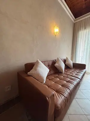 a brown leather couch in a room with a window at Palmeraie village , lieu exceptionnel avec jardin et piscine in Marrakech