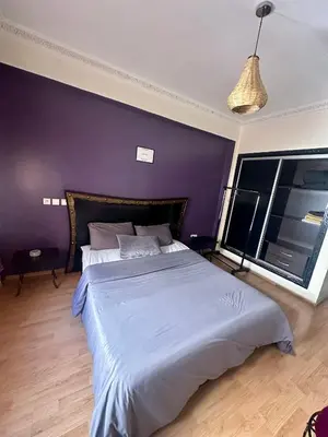 a bedroom with a large bed with a purple wall at apartement centre gueliz in Marrakech