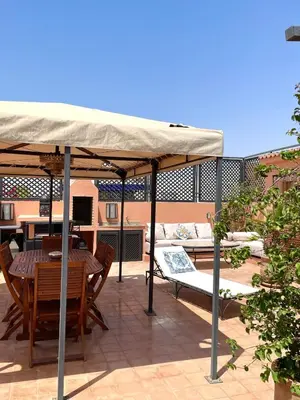 a table and chairs under an umbrella on a patio at Rooftop Sun Pool Chic Apartment Perfect Stay in Marrakech
