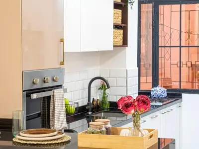 a kitchen with white cabinets and red roses in a vase at NEW Cocon cosy au coeur de Marrakech in Marrakech