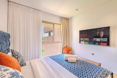 a bedroom with a bed with a tv on the wall at Luxury Apartment - Prestigia Golf City Marrakech in Marrakech
