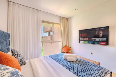 a bedroom with a bed with a tv on the wall at Luxury Apartment - Prestigia Golf City Marrakech in Marrakech