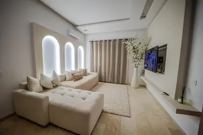 a living room with a white couch and a tv at Prestigia Apartment Secure Residence Pool in Marrakech