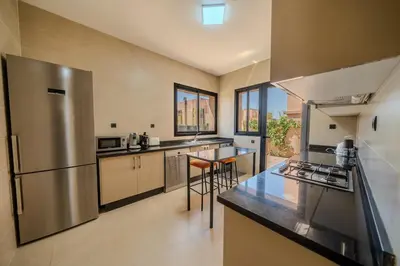 a large kitchen with a stainless steel refrigerator and counters at Villa Assia Modern Luxury Private Pool in Marrakech