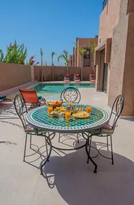 a glass table with food on it next to a pool at Villa Assia Modern Luxury Private Pool in Marrakech