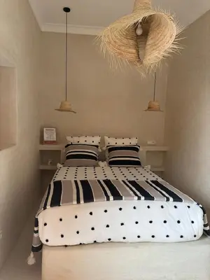 a bedroom with a large bed with black and white pillows at Riad Dar tiegezh in Marrakech