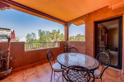 a patio with a table and chairs on a balcony at Marrakech-Piscines-Salle Sport - 5 min du stade in Marrakech
