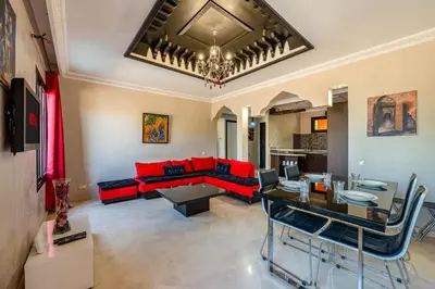 a living room with a red couch and a table at Marrakech-Piscines-Salle Sport - 5 min du stade in Marrakech