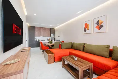 a living room with an orange couch and a television at Modern Comfort in Heart of Marrakech in Marrakech