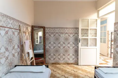 a room with two beds and a mirror and a door at Authentic Moroccan Stay Steps from Jemaa el-Fna in Marrakech