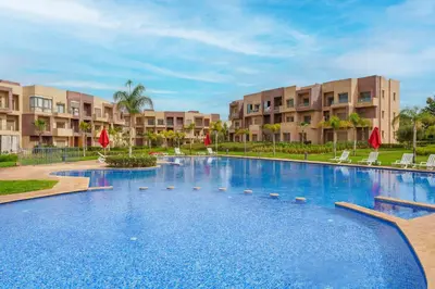 a large swimming pool in front of apartment buildings at Le Lys - Prestigia Argan - Golf - 6 Prs - Piscine in Marrakech