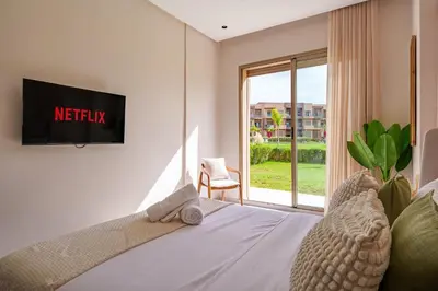 a bedroom with a bed with a television on a wall at Le Lys - Prestigia Argan - Golf - 6 Prs - Piscine in Marrakech