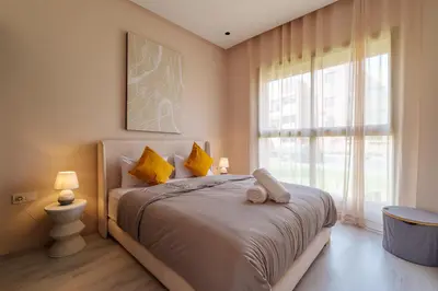 a bedroom with a bed with yellow pillows and a window at Le Lys - Prestigia Argan - Golf - 6 Prs - Piscine in Marrakech