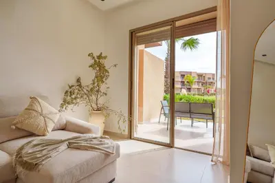 a living room with a couch and a sliding glass door at Le Lys - Prestigia Argan - Golf - 6 Prs - Piscine in Marrakech
