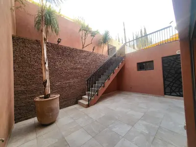 a house with a staircase and a palm tree in a courtyard at Magnifique villa spacieuse Route de l'ourika in El Rhechat