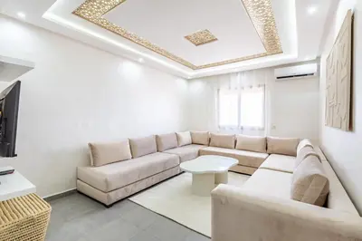a living room with a couch and a tv at Magnifique appartement 2 chambres route du barrage in Marrakech