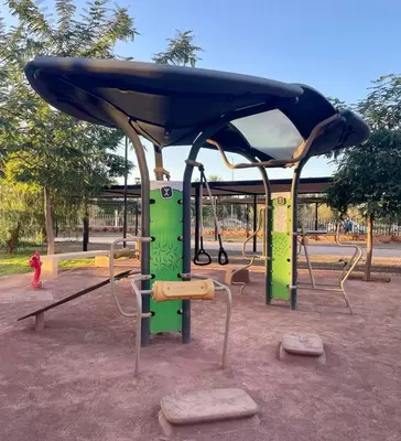 a playground in a park with a blue canopy at ART NORIA Private garden - pool view in Marrakech