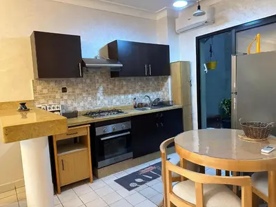a kitchen with black cabinets and a table with chairs at Elégance marrakech in Marrakech