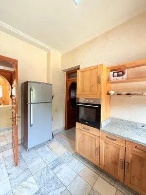 a kitchen with a refrigerator and wooden cabinets at VILLA 33 - 4 Master Suites, Stylish Moroccan Design & Private Pool in Marrakech