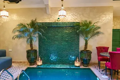 a swimming pool in a hotel room with palm trees at Riad Lia ou Lik in Marrakech