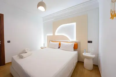 a white bedroom with a bed and a toilet at Gueliz Central Apartment with Pool and Parking in Marrakech