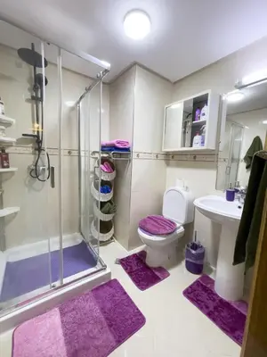a bathroom with a shower and a toilet and purple mats at Appartement privé au cœur de Marrakech in Marrakech