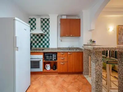 a kitchen with wooden cabinets and a white refrigerator at Majorelle Appartement - Balcony and Netflix in Marrakech