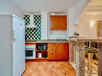 a kitchen with wooden cabinets and a white refrigerator at Majorelle Appartement - Balcony and Netflix in Marrakech