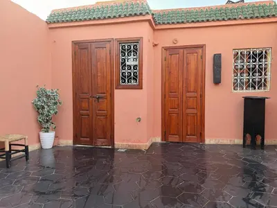 a pink house with two wooden doors and a table at Amber in Marrakech