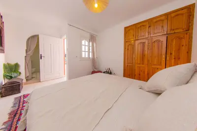 a bedroom with a large white bed with a wooden cabinet at Riad Dahab in Marrakech
