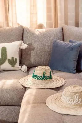 two hats are sitting on a couch with pillows at Appartement confortable au cœur de Gueliz in Marrakech